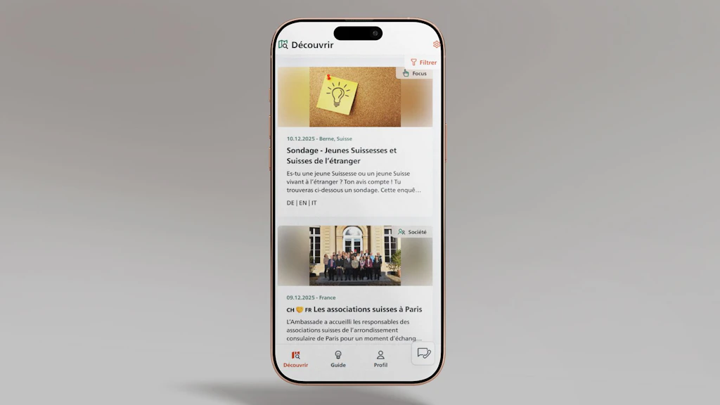 L’image montre un smartphone sur lequel l’application SwissInTouch est ouverte sur le flux de publications. Deux contributions sont visibles.